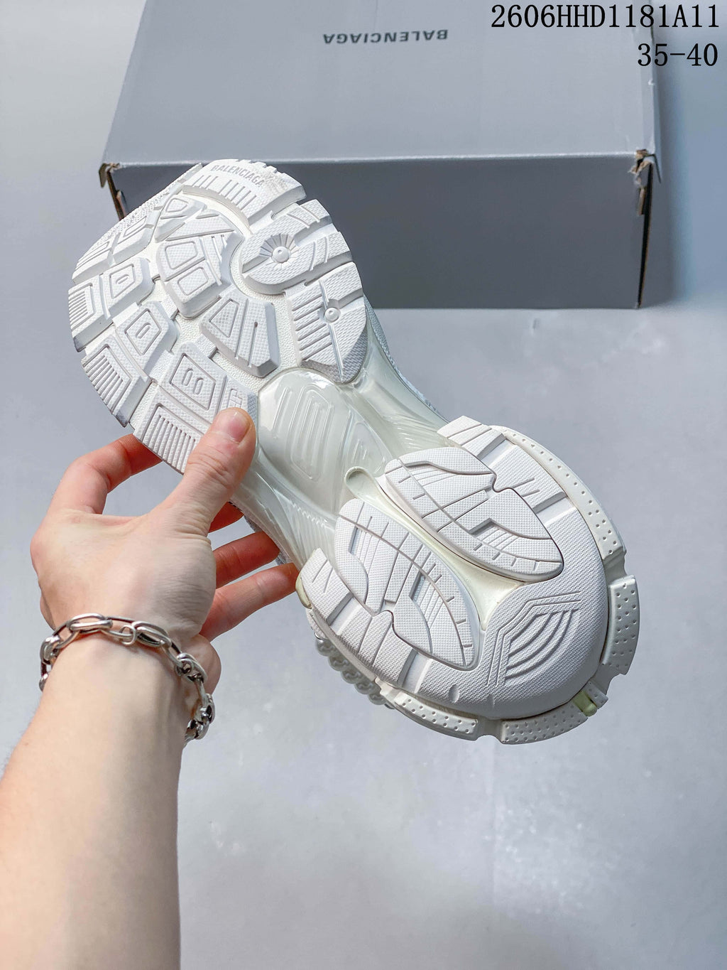 Underside view of the white sneaker showing its patterned outsole and sculpted sole.