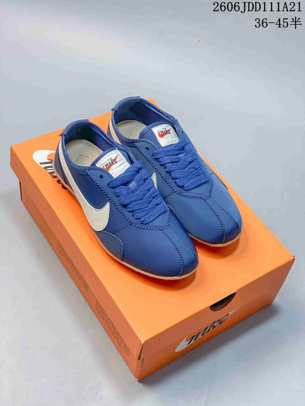 Pair of blue Nike Moon Shoe OG Summit low-top sneakers with white side accents on an orange box