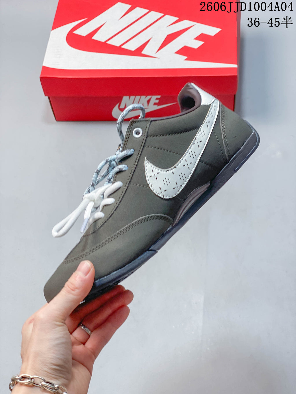 Side view of a gray Nike Sprint Sister sneaker with a perforated light-colored Swoosh