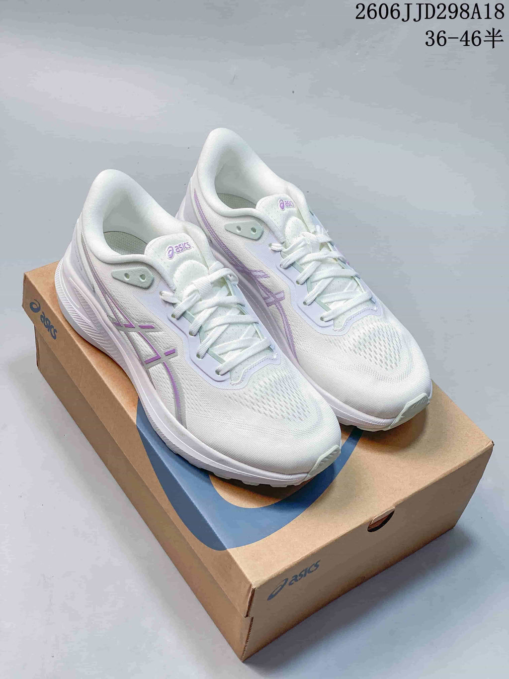 Pair of white ASICS GT-1000 13 Paris running shoes with pale purple accents on a shoebox