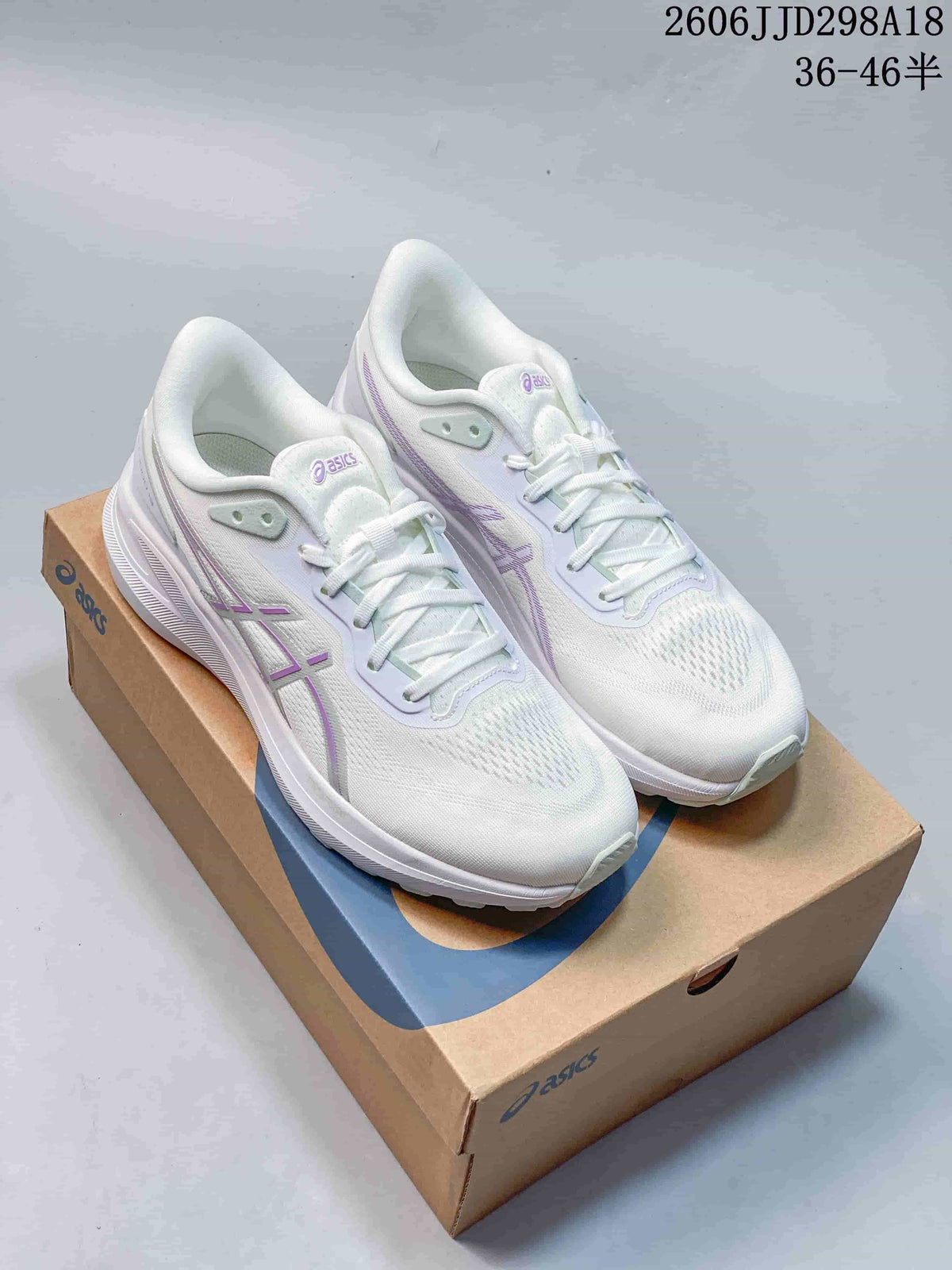 Pair of white ASICS GT-1000 13 Paris running shoes with pale purple accents on a shoebox