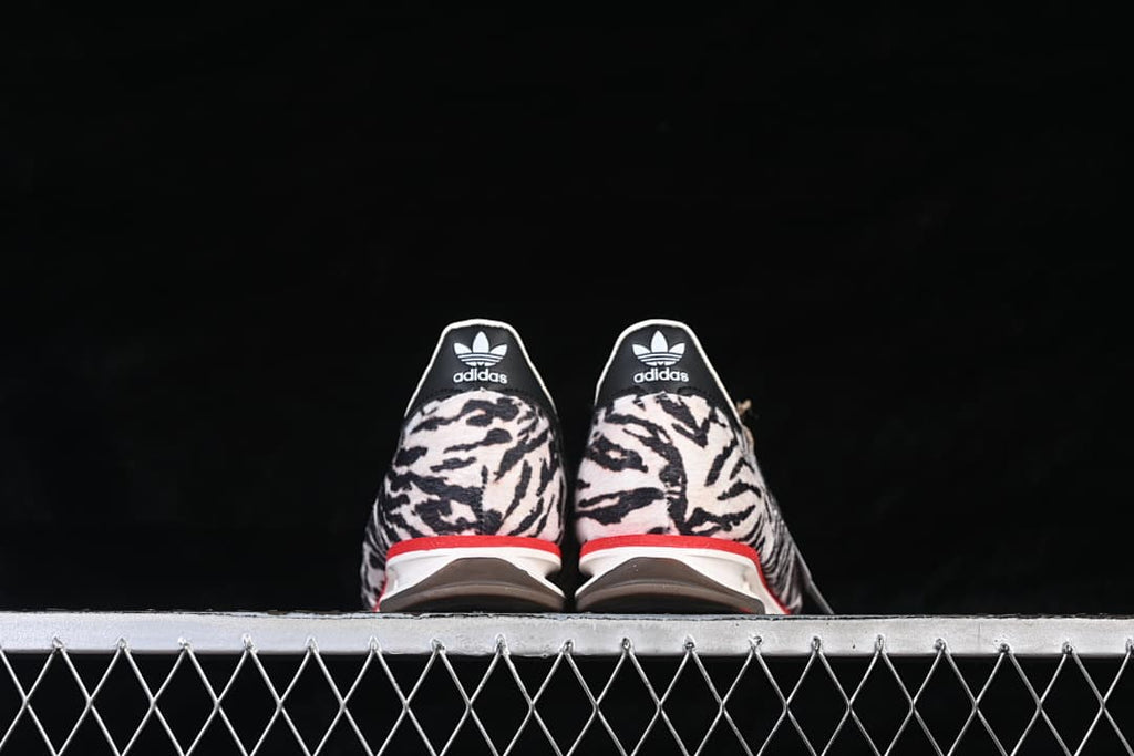 Rear view of both sneakers showing animal-print heels and red midsole accents.