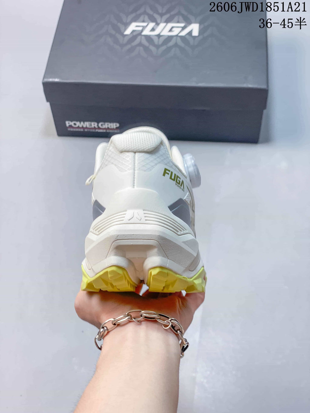 Rear view of a white shoe with a yellow outsole and FUGA branding