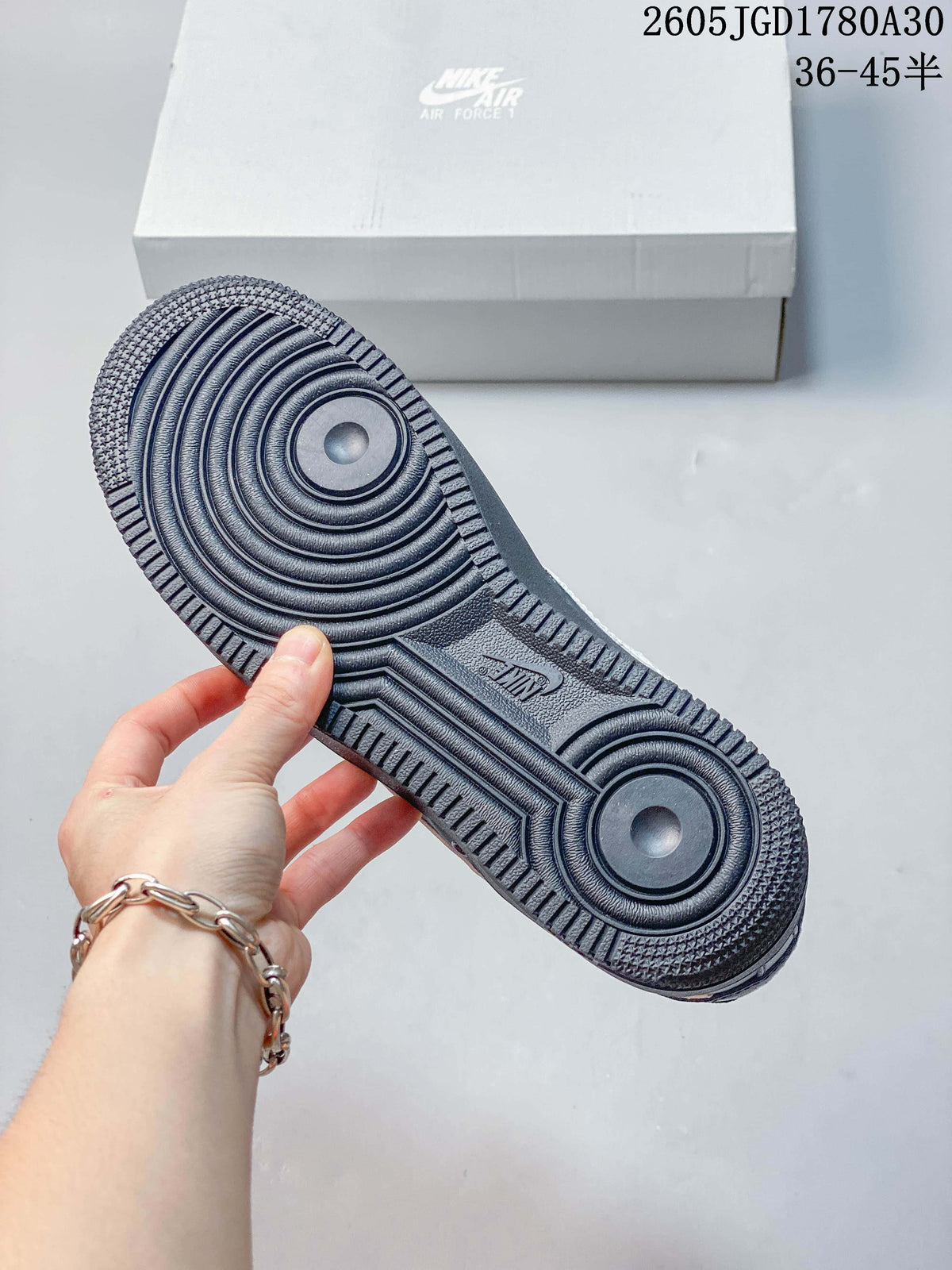 Close-up of the circular-patterned outsole on a dark gray Nike Air Force 1 Low sneaker.
