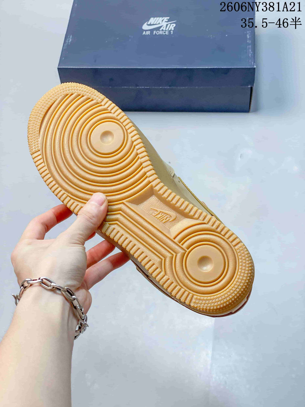 Underside of the tan sneaker showing its circular tread pattern and textured outsole