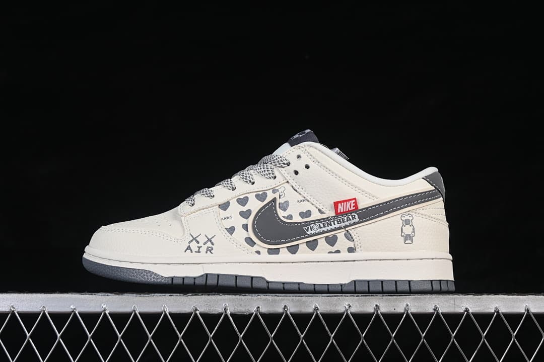 Side view of a white and grey low-top sneaker with heart-patterned panels and graphic accents.