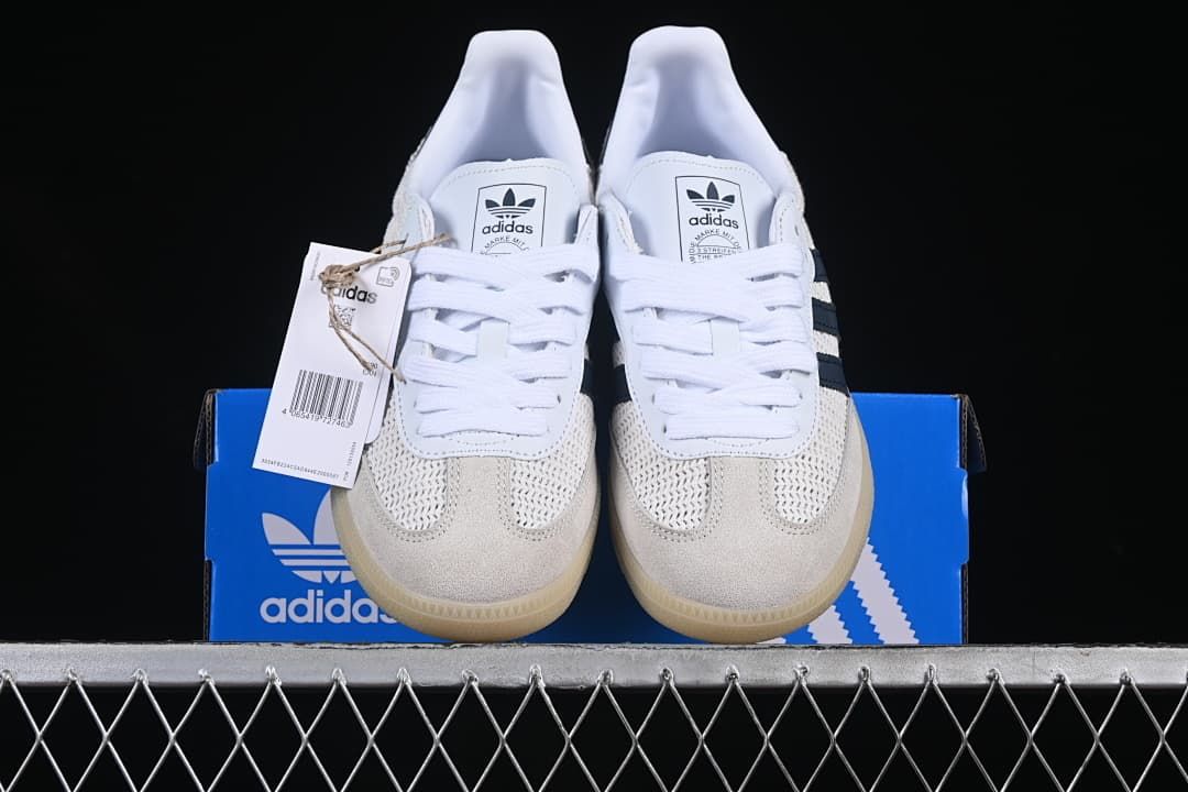 Front view of the pair of white and navy sneakers on a blue shoe box