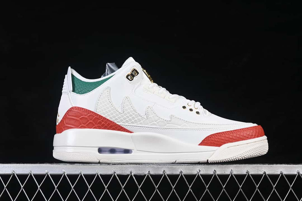 Side view of white Jordan Air Jordan 3 sneakers with red and green accents and gold-tone details