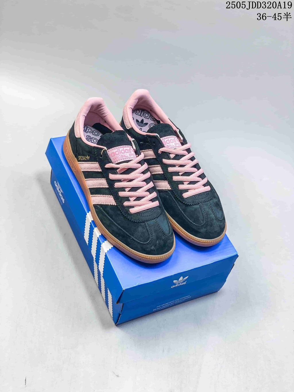 Pair of dark adidas Originals low-top sneakers with pink accents and gum soles on a blue shoe box