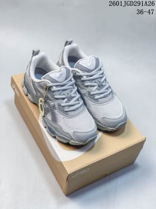 Pair of light-gray and white ASICS GEL-NYC RGD sneakers displayed on a product box with a decorative lace accessory; image text shows code 2601JGD291A26 and sizes 36–47.