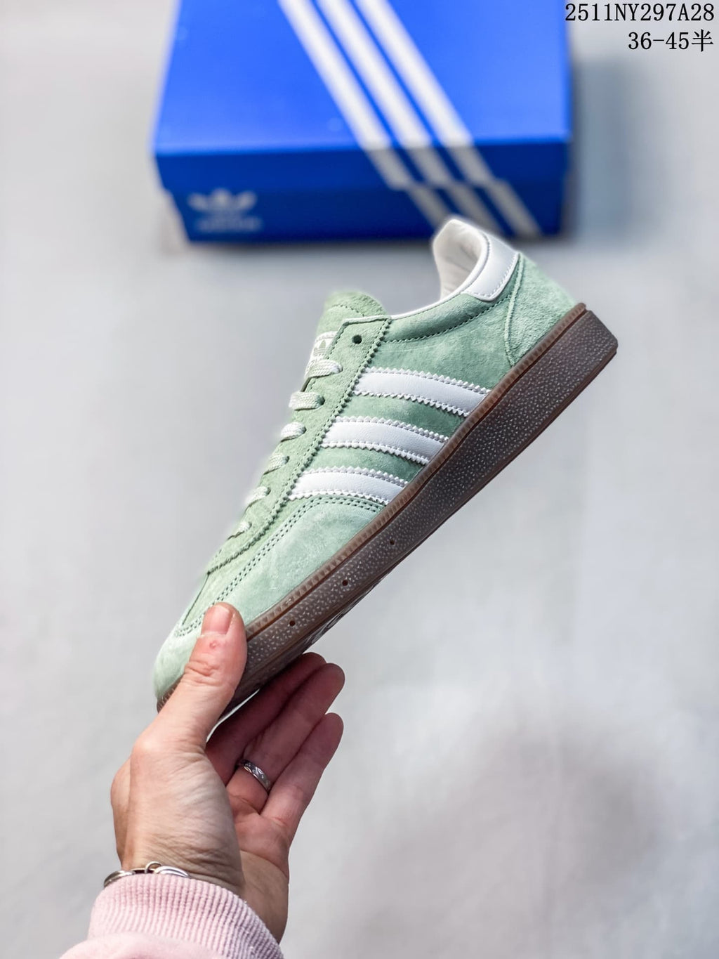 Side view of a pale green adidas Handball Spezial sneaker with white stripes and a brown outsole.