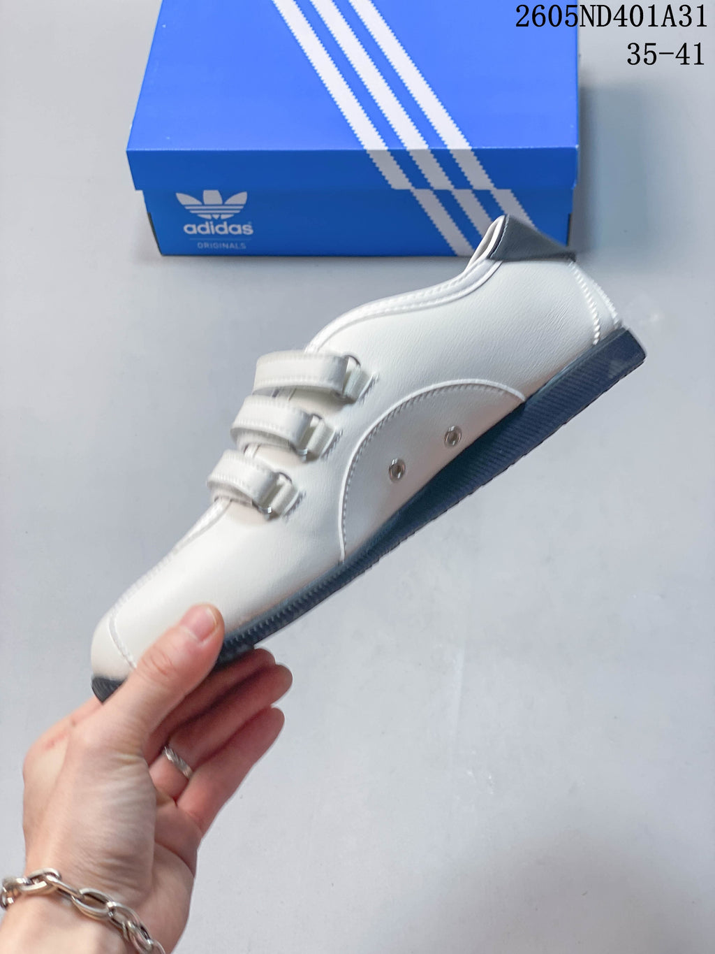Side profile of the white low-top sneaker with three straps and gray accents.