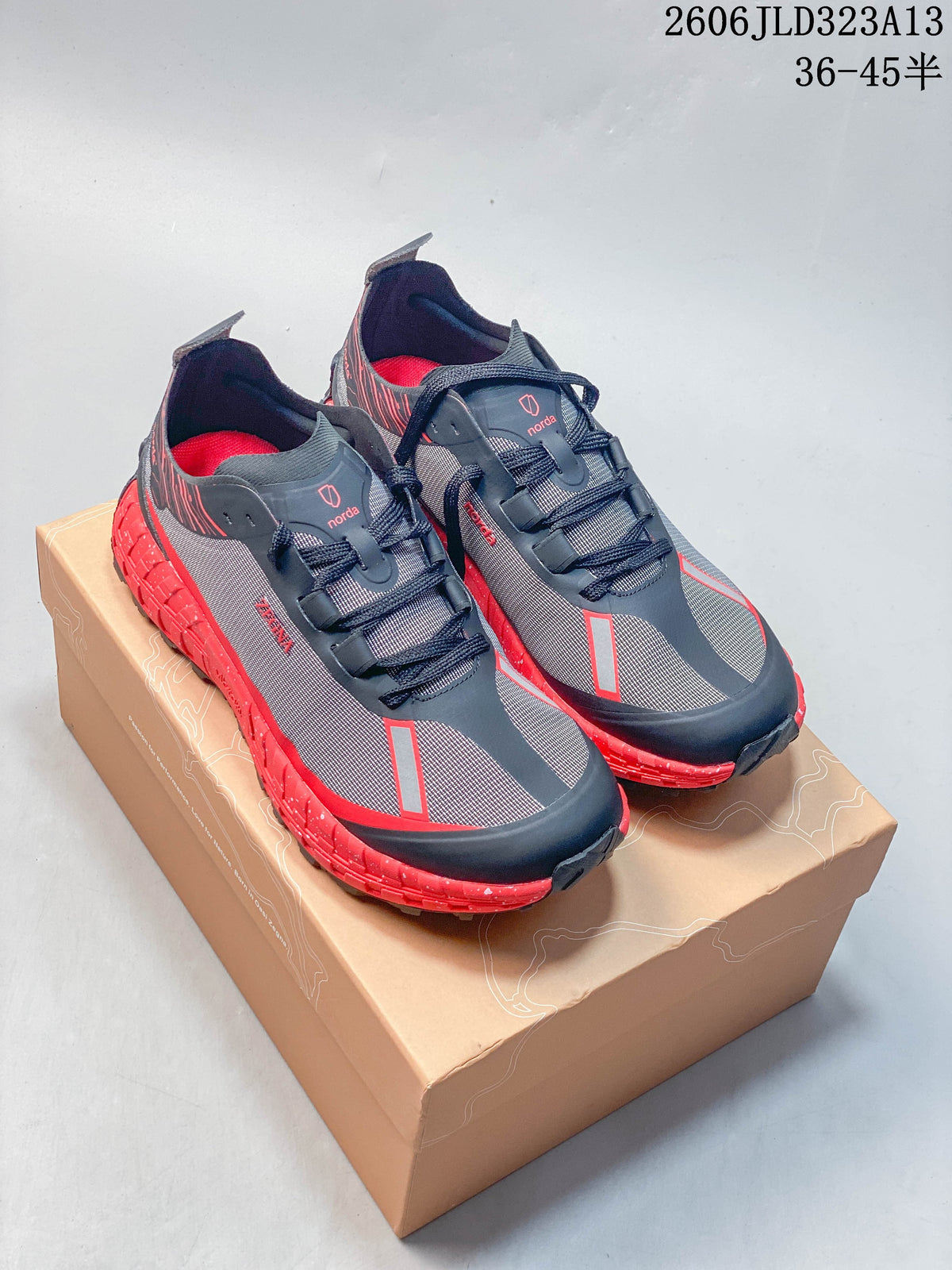Pair of charcoal and red Norda 001 trail-running shoes on a box