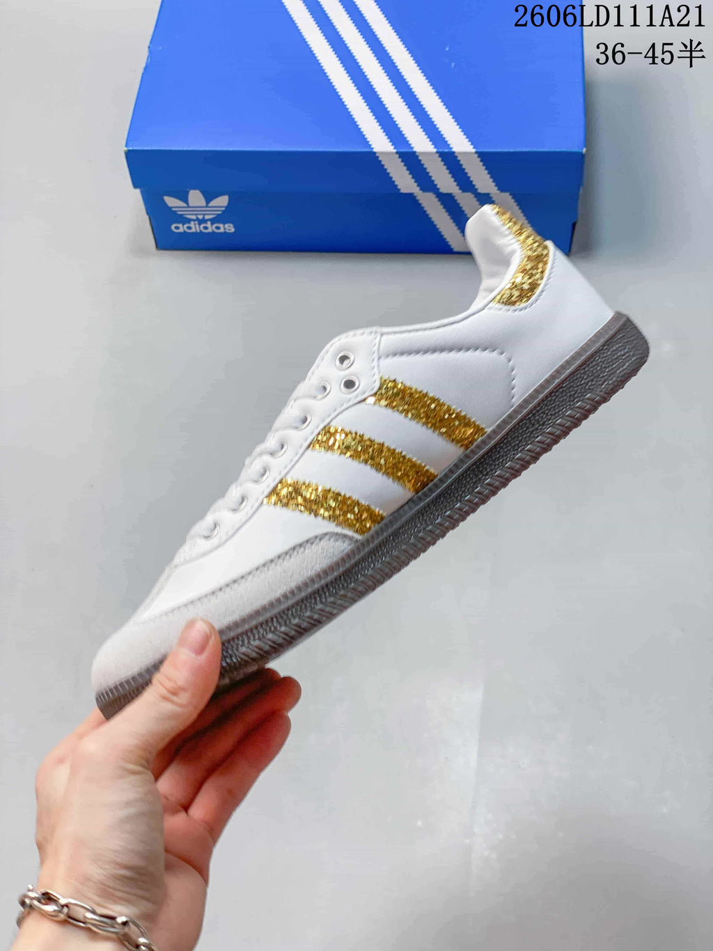 Side view of the white low-top sneaker with gold-glitter stripes and light-colored toe overlay.