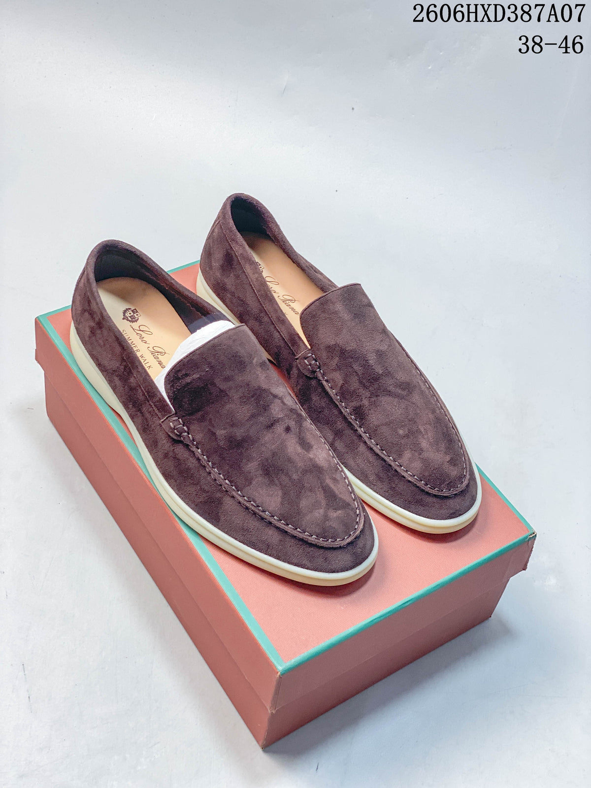 Pair of brown-toned slip-on loafers with apron toes and light-colored soles, shown on a box.