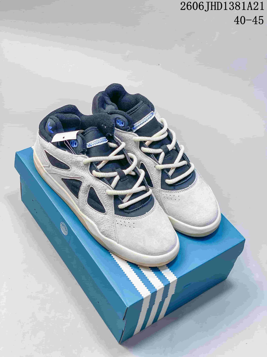Pair of grey and navy adidas Bad Bunny Badbo 1.0 high-top sneakers on a blue box