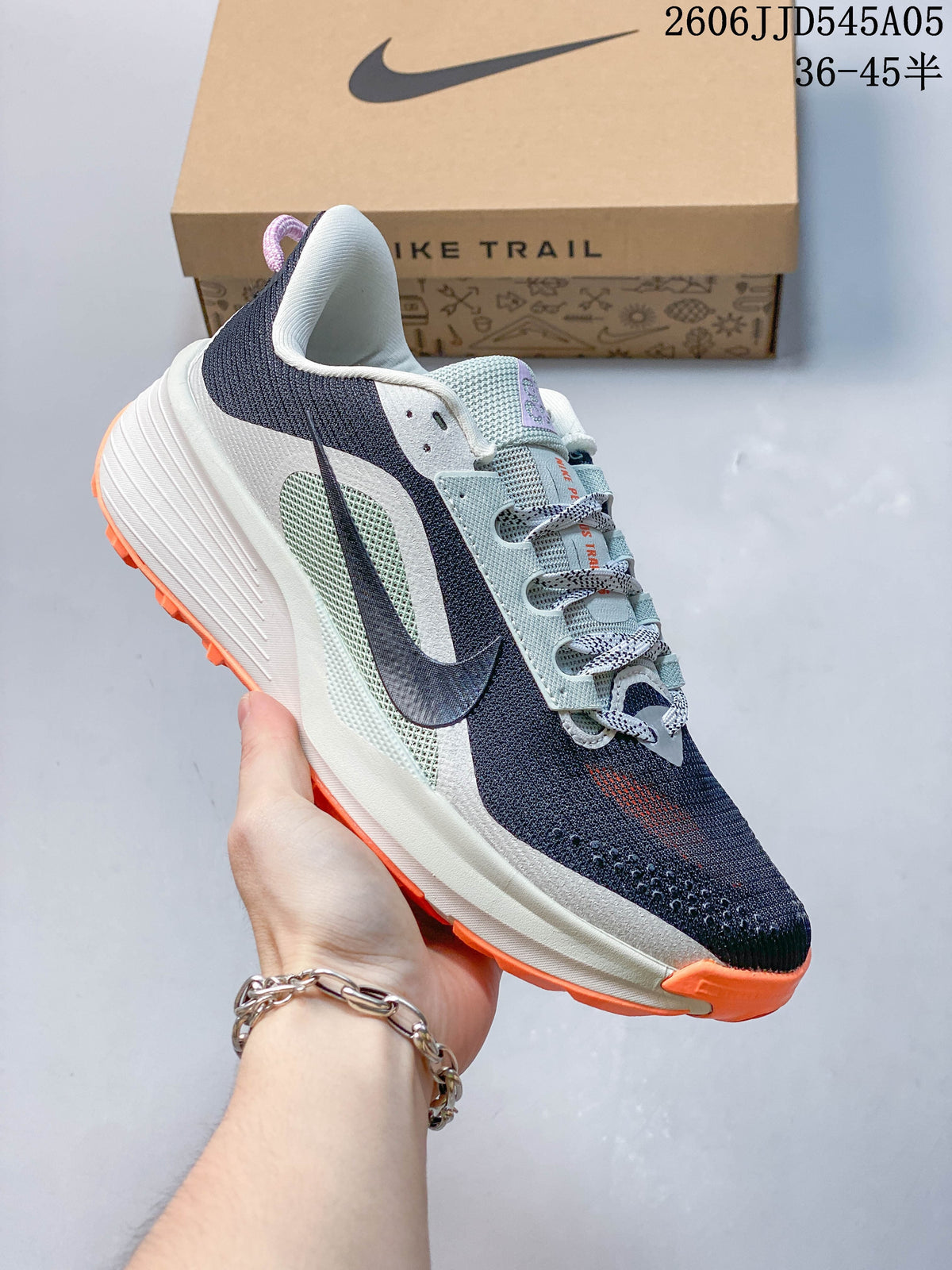 Side view of a navy Nike Pegasus Trail 6 shoe with orange outsole accents