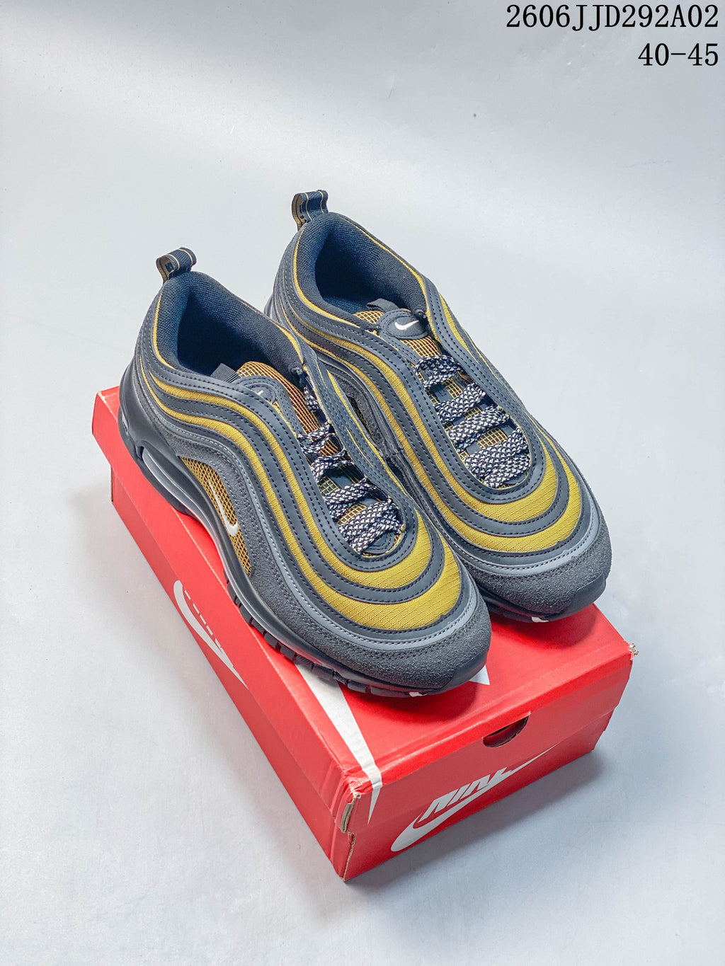 Nike Air Max 97 sneakers in gray, yellow, and navy, shown from above on a red shoebox