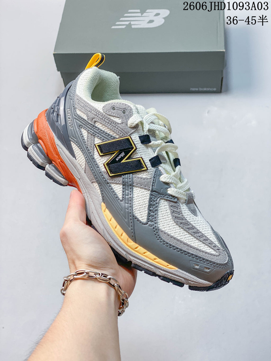 White and gray New Balance 1906U sneaker with orange accents