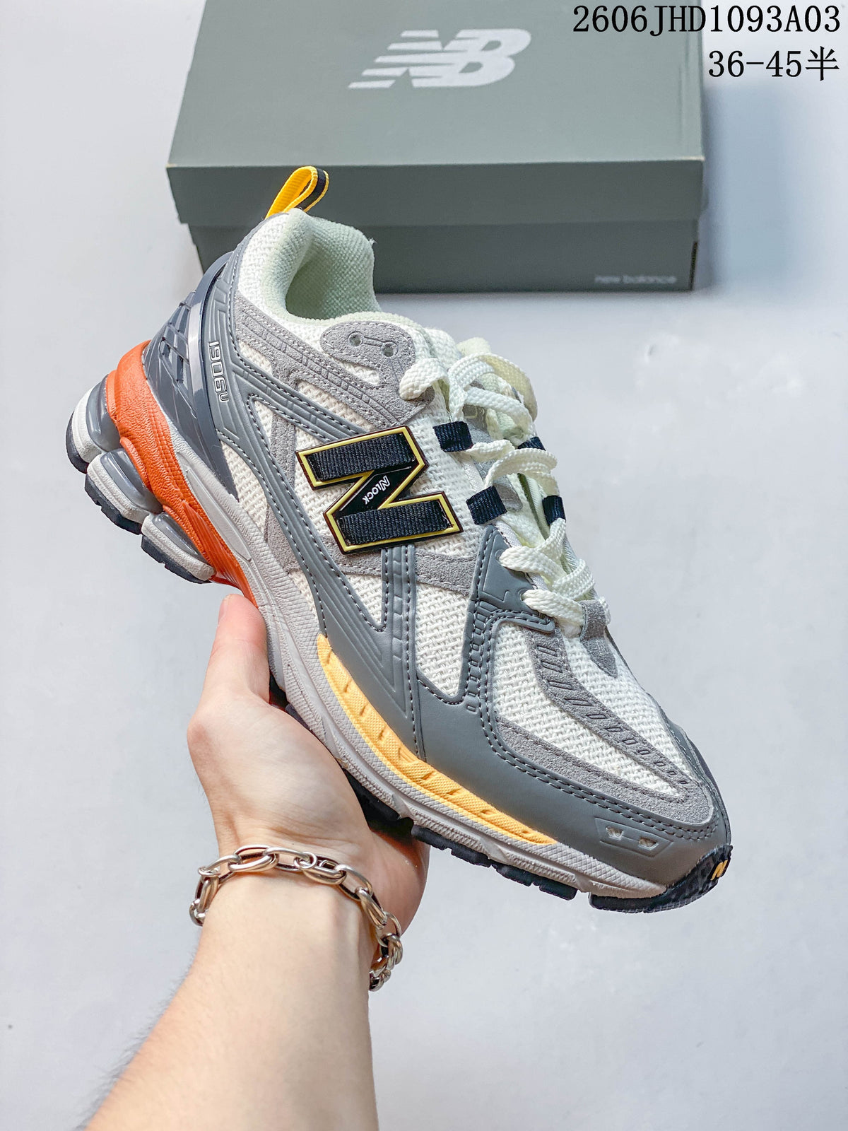 White and gray New Balance 1906U sneaker with orange accents