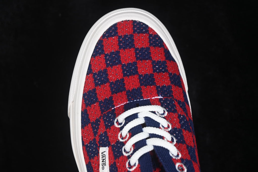 Close-up of the red and navy check-pattern toe box, white laces, and Vans side label.