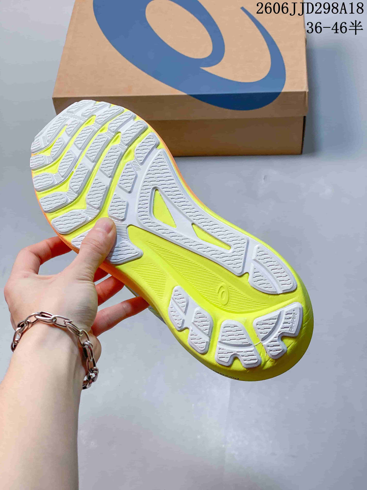 Underside of the running shoe showing a segmented white and lime outsole
