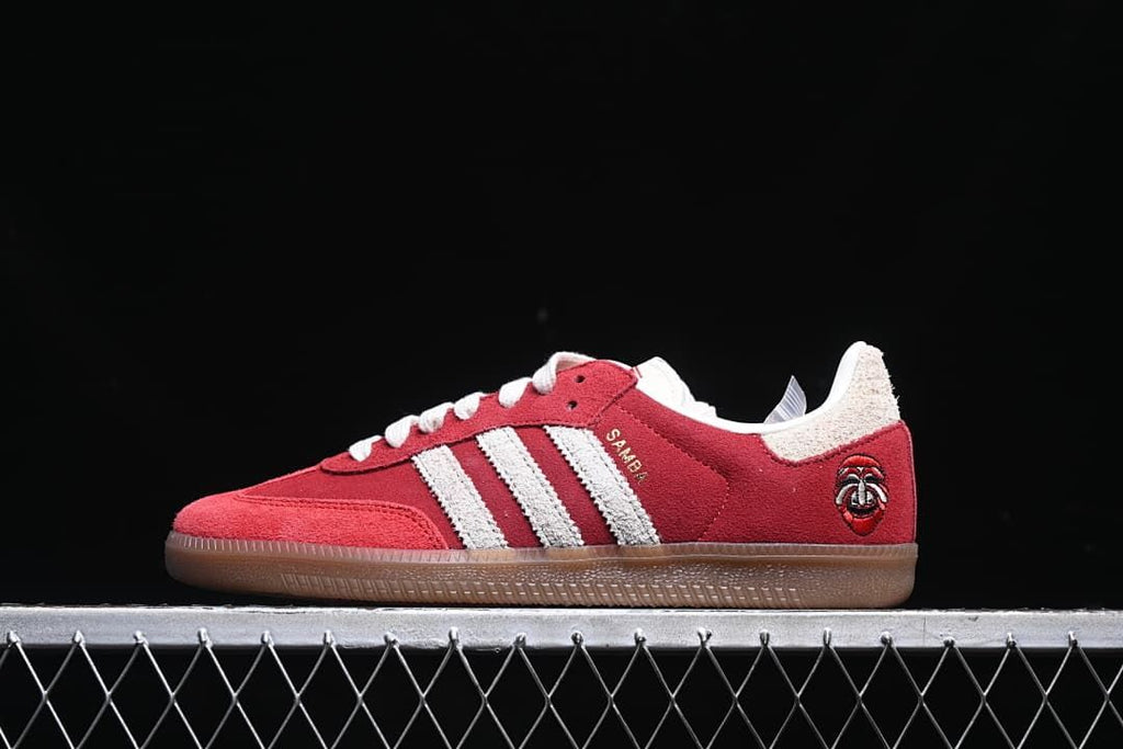 Side profile of a red Samba OG Tal sneaker with off-white stripes and a gum-colored outsole.