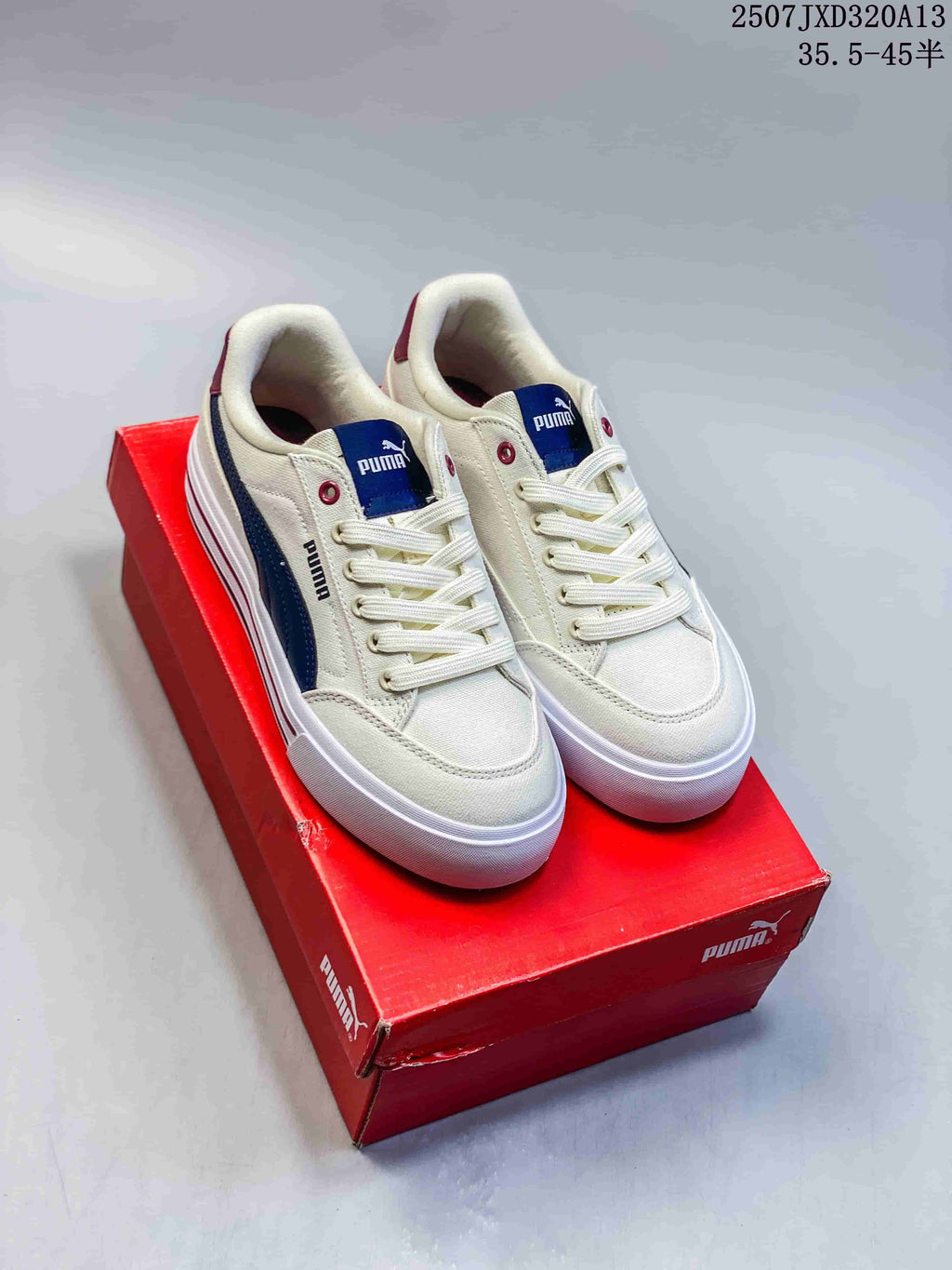 Pair of cream PUMA low-top sneakers with navy and burgundy accents, shown on a red shoebox.