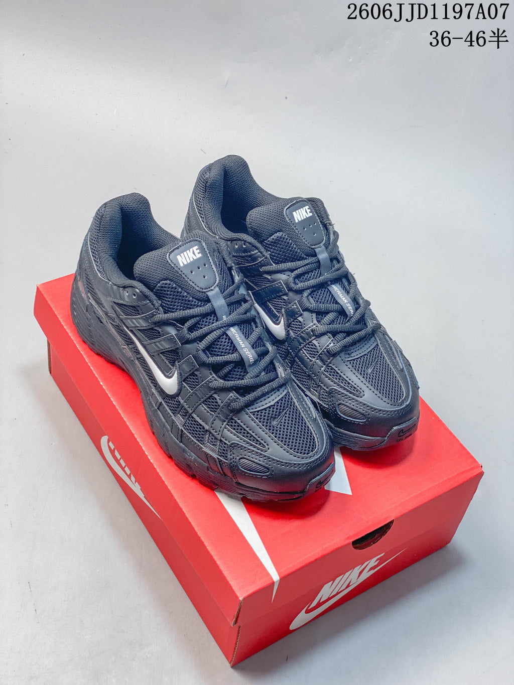 Pair of dark gray Nike P-6000 style sneakers on a red shoe box
