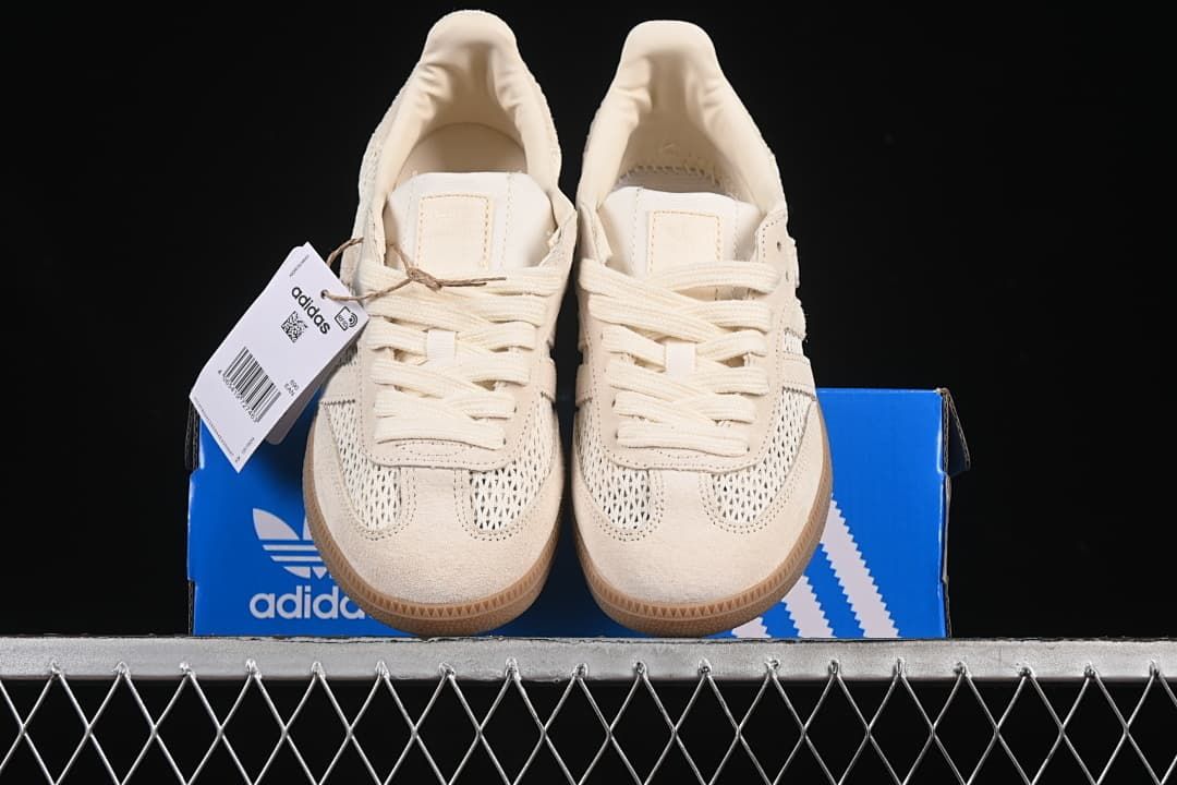 Front view of the pair of cream sneakers resting on a blue adidas box.