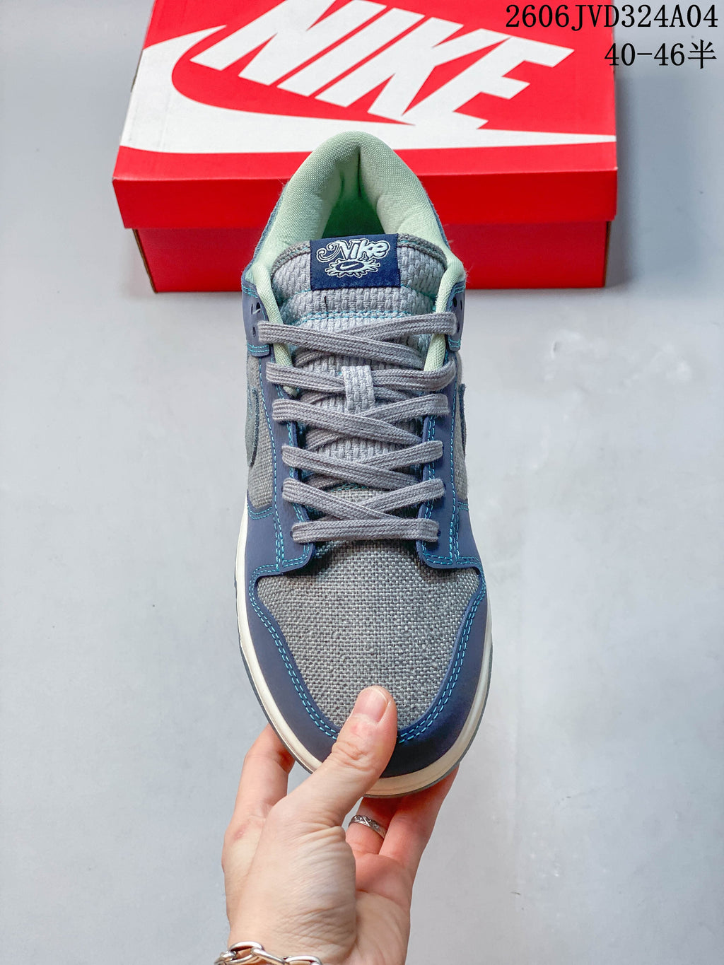 Front view of a gray and blue Nike Dunk Retro SE sneaker with gray laces
