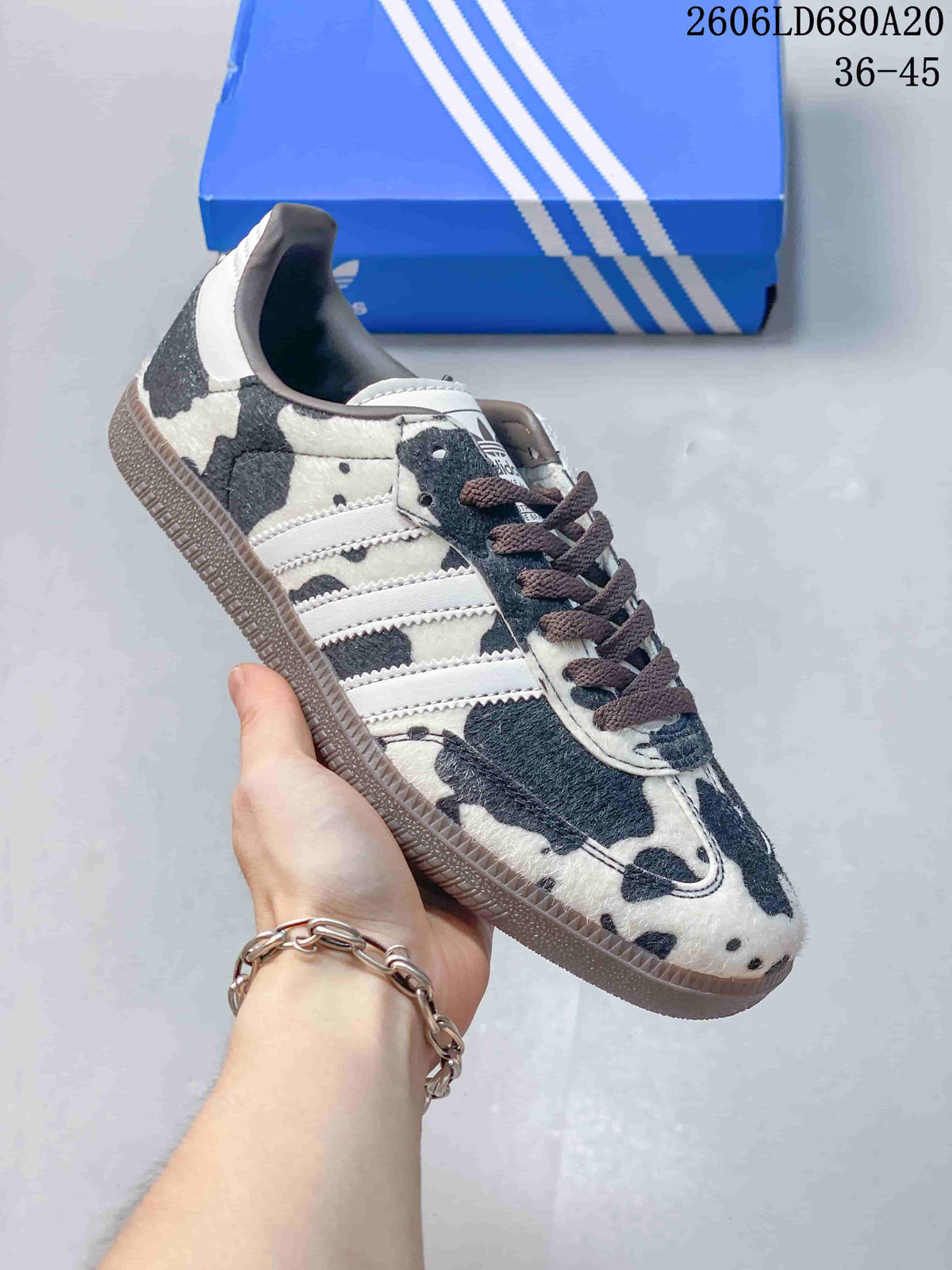 Black-and-white cow-print low-top sneaker with white side stripes and a dark gum-look sole
