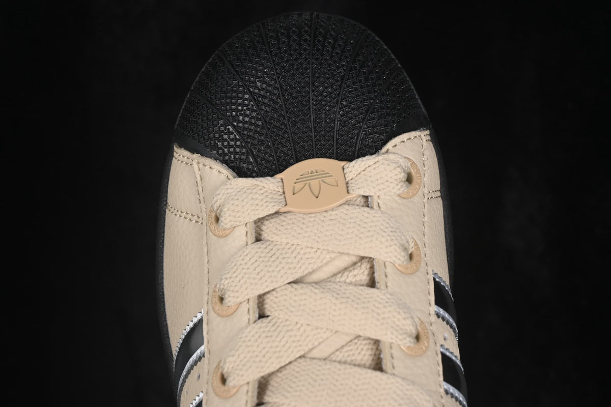 Close-up of the beige laces, eyelets, tongue tab, and textured black shell toe.