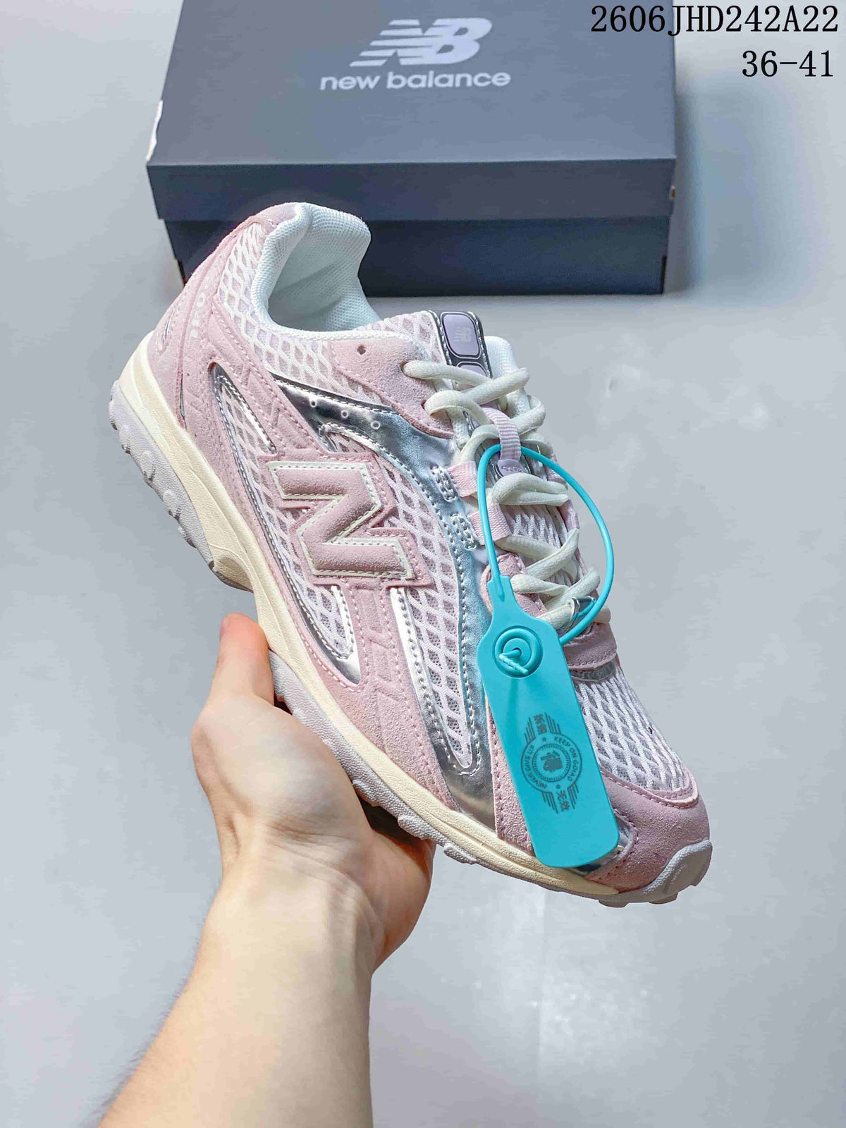 Angled side view of a pink and silver sneaker with a turquoise tag.