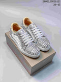 Pair of silver patterned low-top sneakers with metallic studs, white laces, and red soles