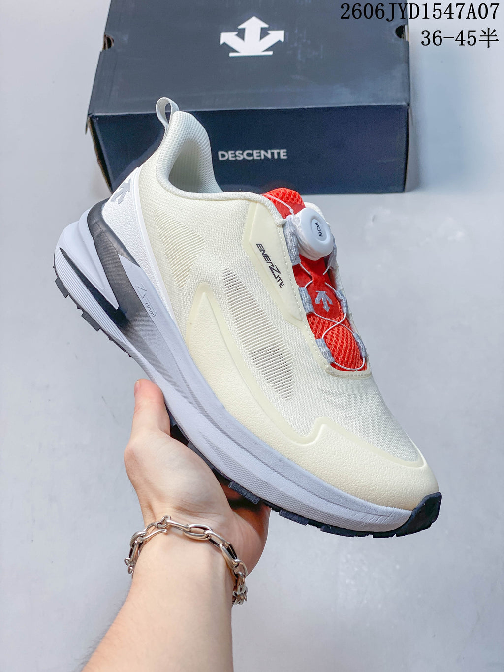 Angled side view of a cream DESCENTE shoe with red closure details and a layered sole.