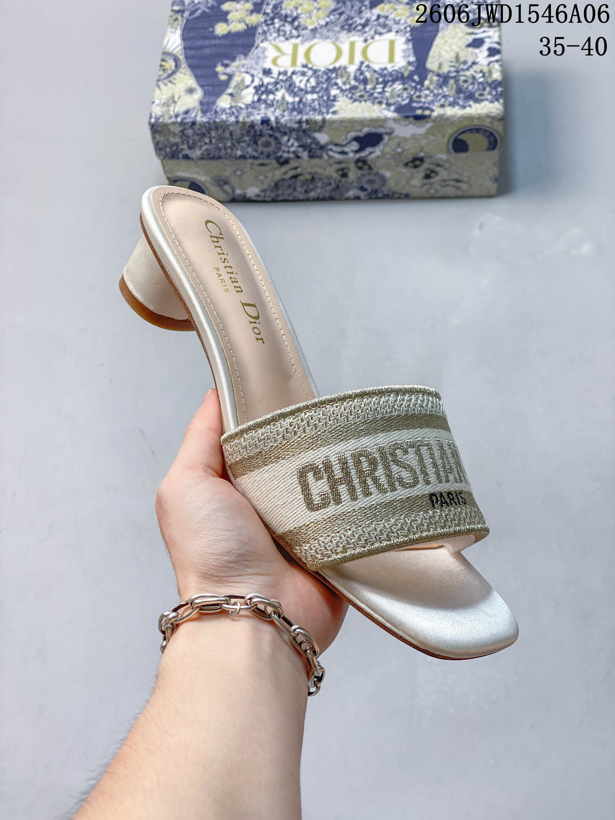 Angled view of a gold-toned embroidered mule sandal