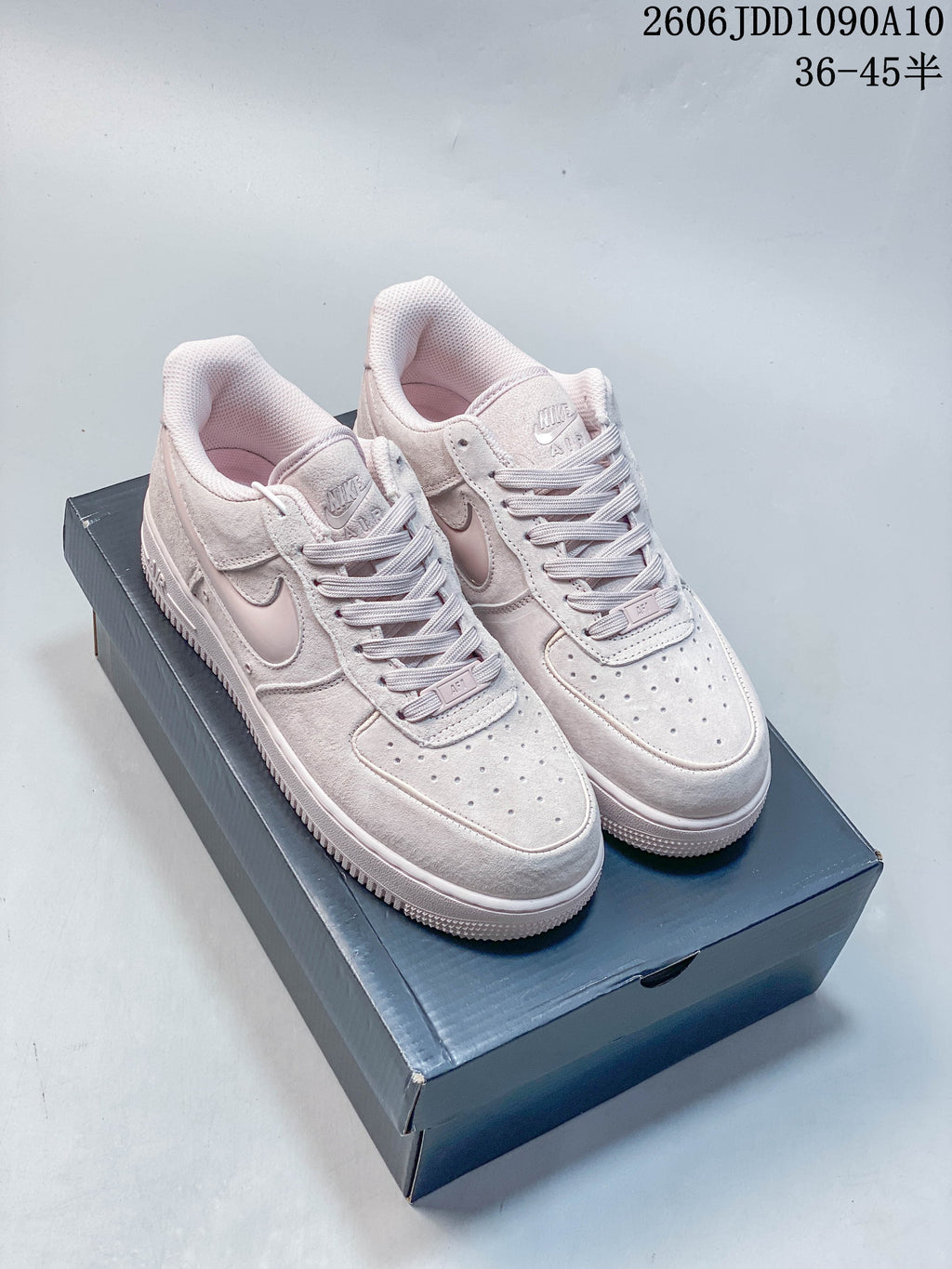 Pair of pale pink Nike Air Force 1 low-top sneakers displayed on a shoe box.