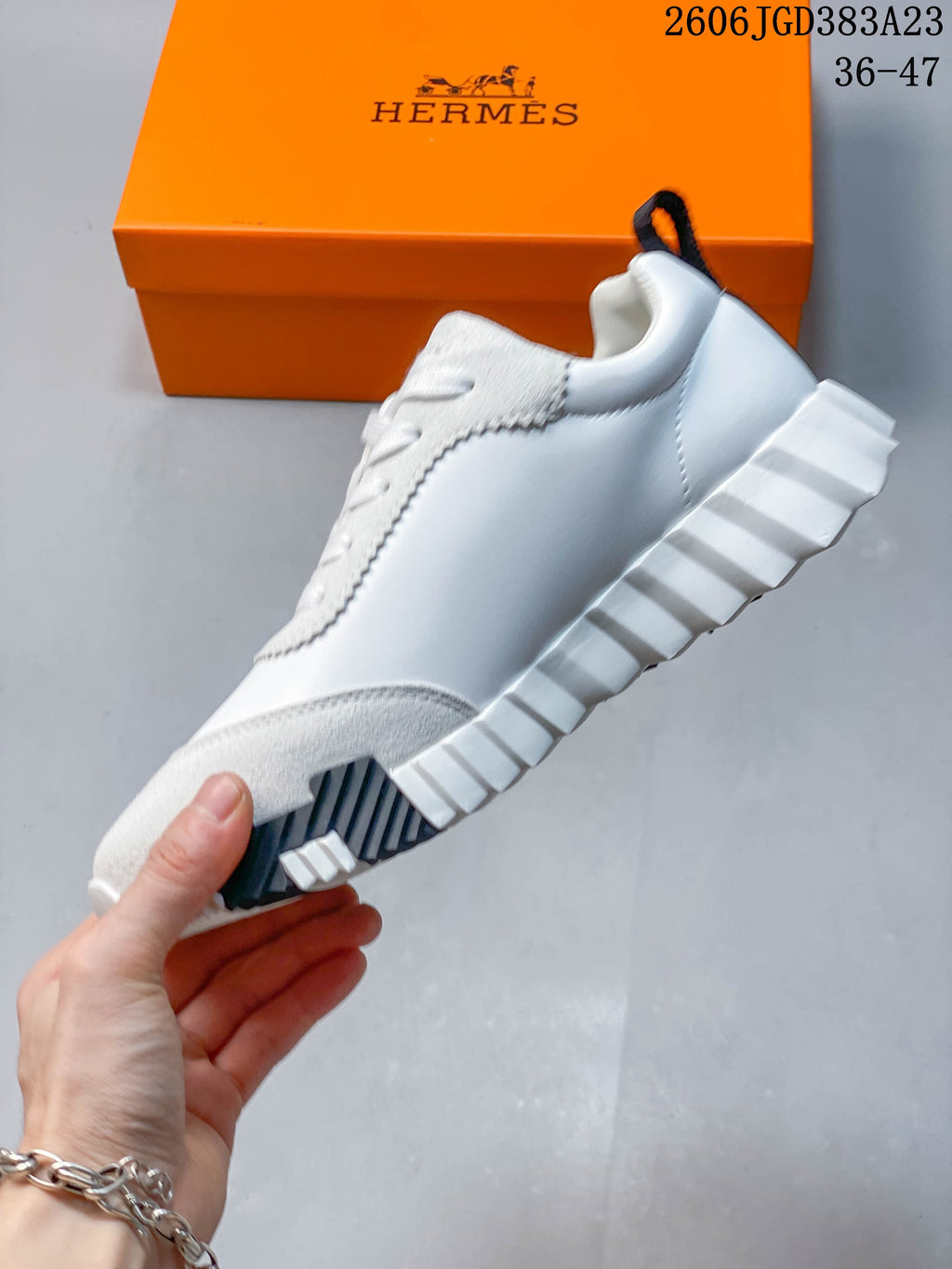 Side view of the white low-top sneaker with gray toe overlay, dark heel detail, and ridged sole.