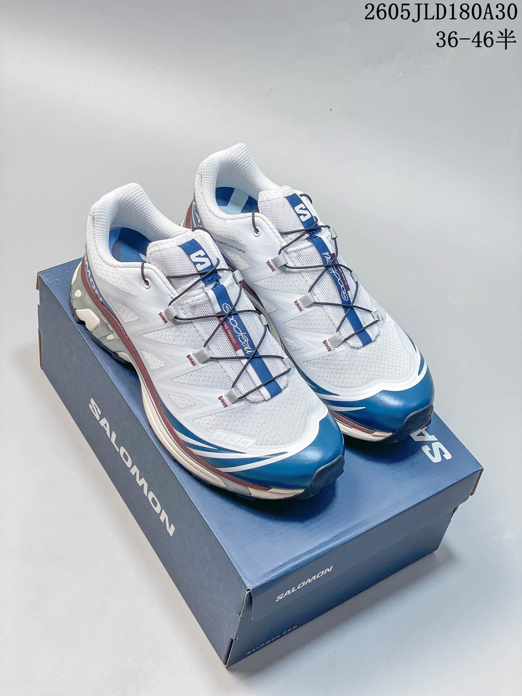 White and blue Salomon XT-6 shoes displayed on a blue shoebox