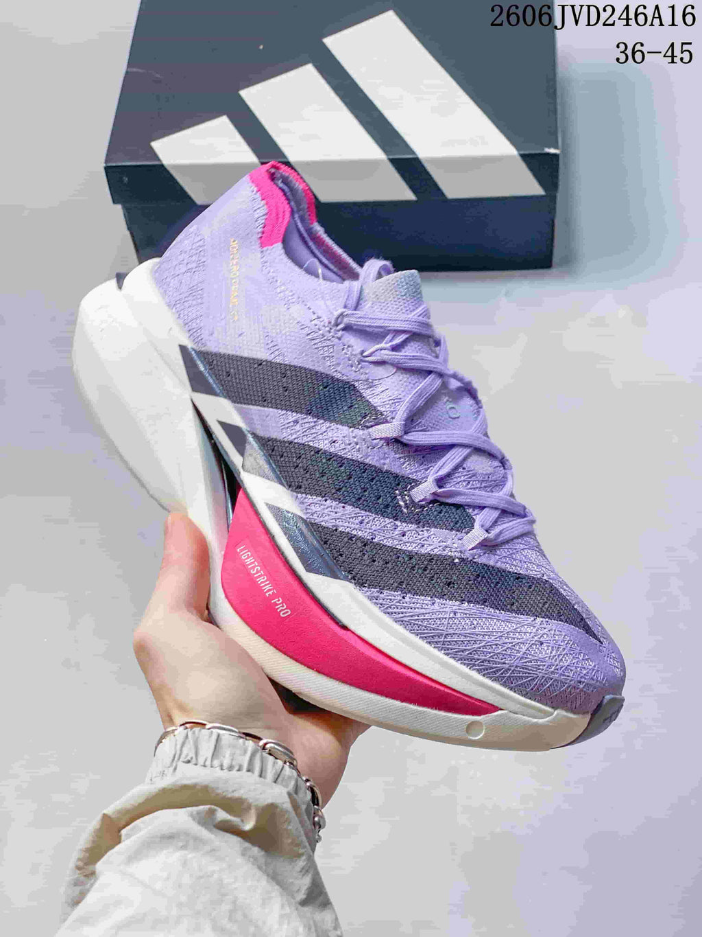 Close side view of a lavender running shoe with dark stripes and a bright pink midsole accent