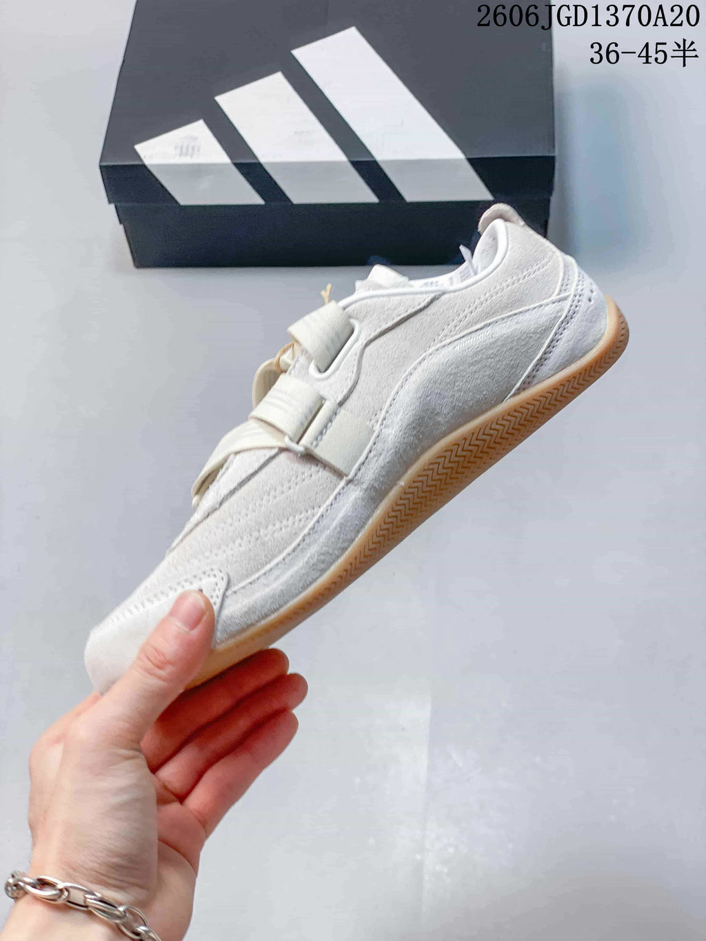 Side view of the light-colored low-top shoe with broad straps and gum outsole