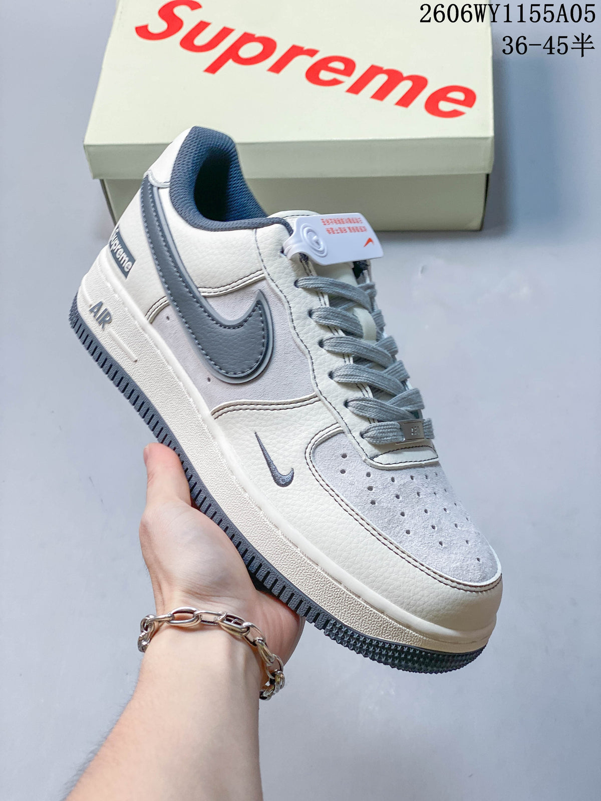 Angled view of a white and slate-blue low-top sneaker with a Supreme-branded heel tab