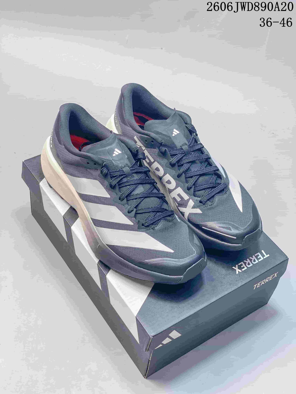 Pair of gray adidas Terrex trail running shoes with white stripes, shown on a shoe box