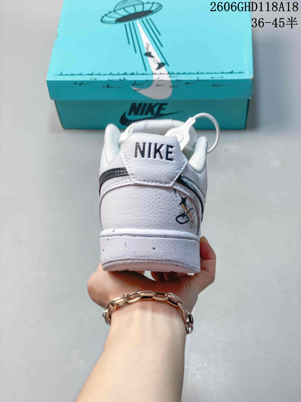 Heel view of a white sneaker with a Nike-branded heel tab and graphic detail.