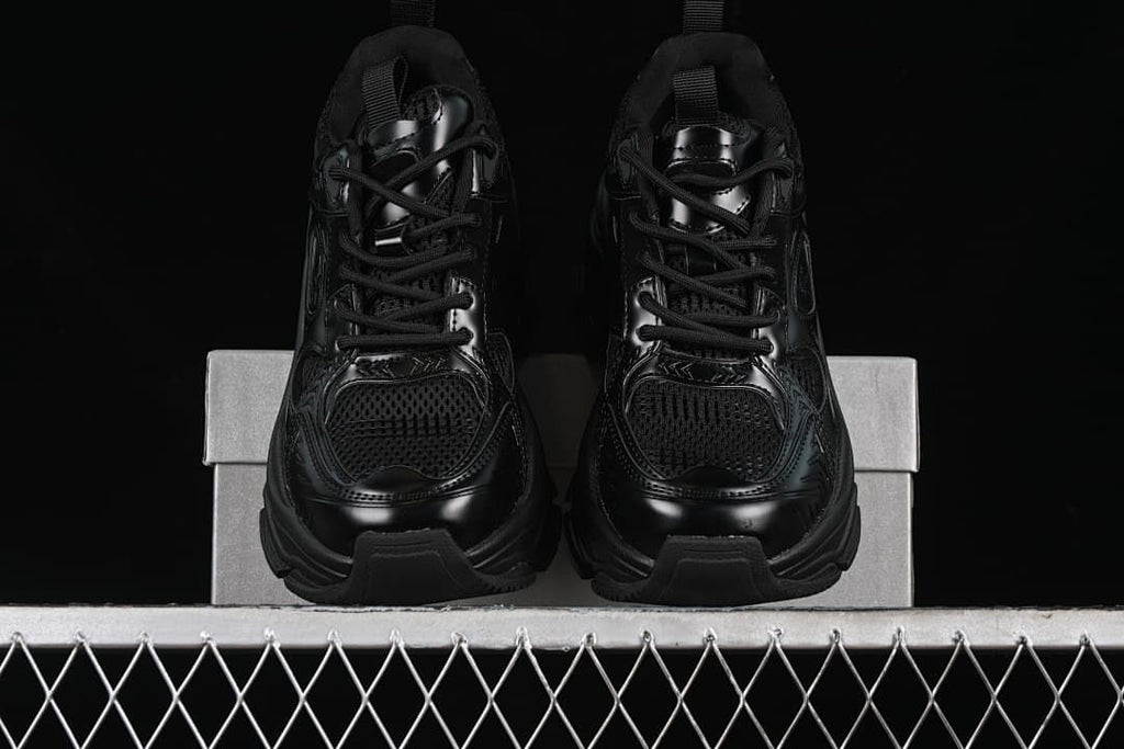 Front view of the pair of black lace-up sneakers on a shoe box.