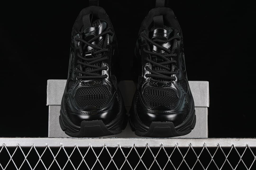 Front view of the pair of black lace-up sneakers on a shoe box.