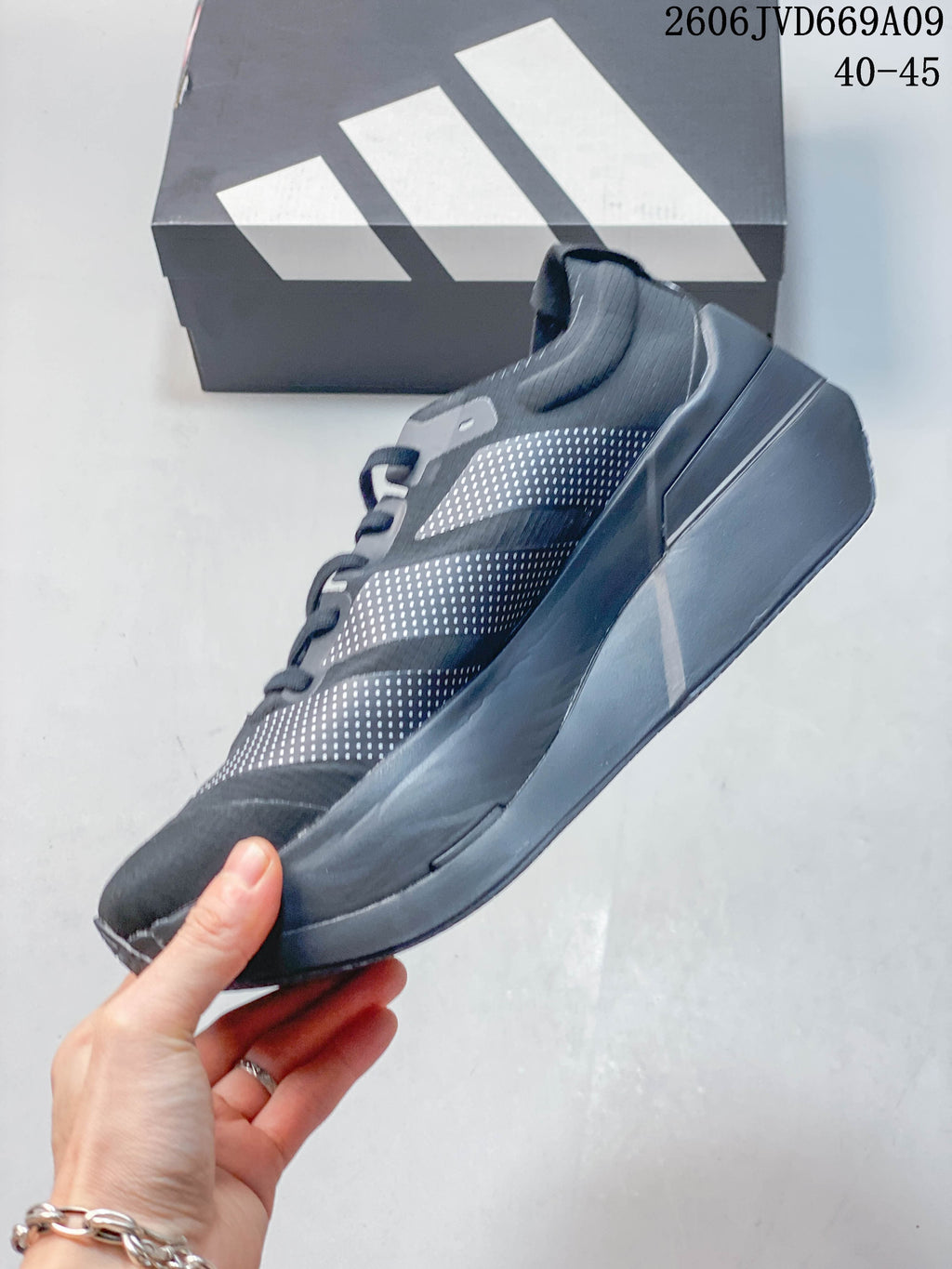 Side profile of a dark gray Adidas shoe with dotted stripe panels