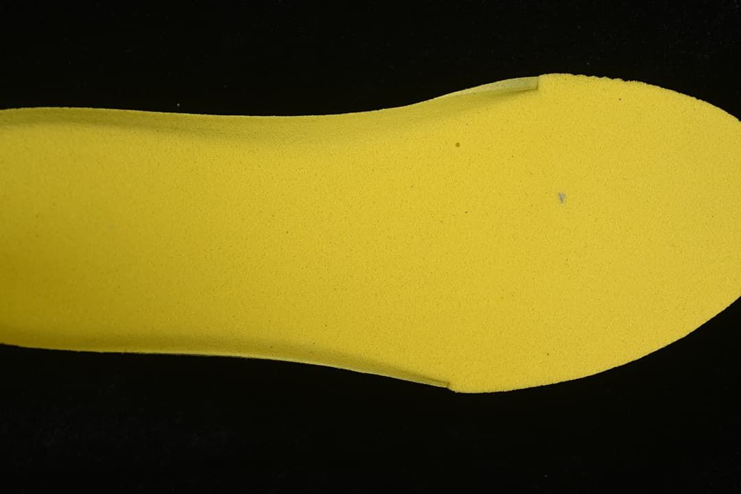 Yellow shoe insert shown against a dark background