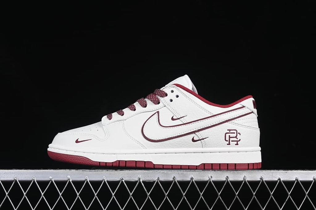 Side view of a white and burgundy Reigning Champ Nike SB Dunk Low sneaker